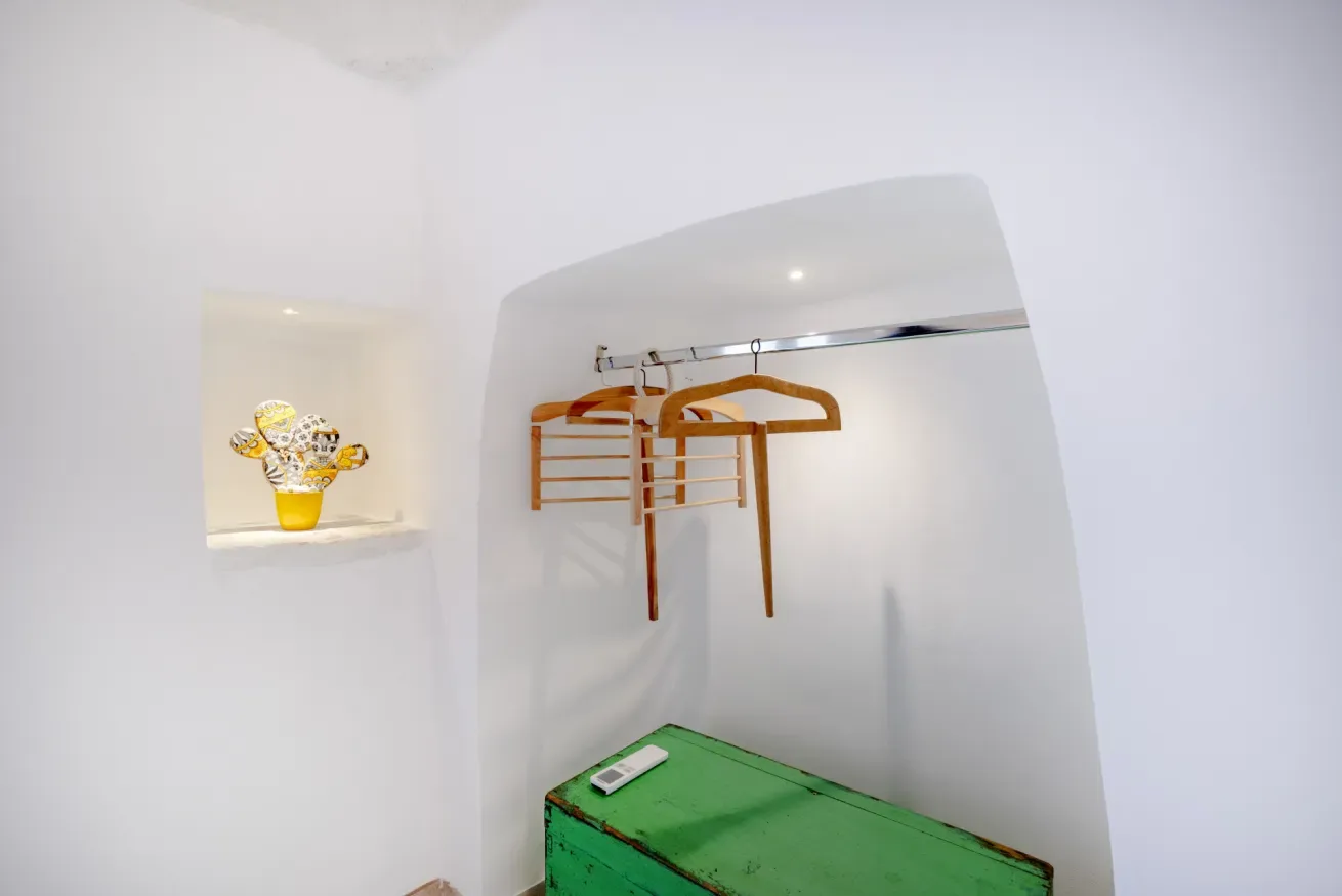 A small dressing area has a clothes rail above a green chest.