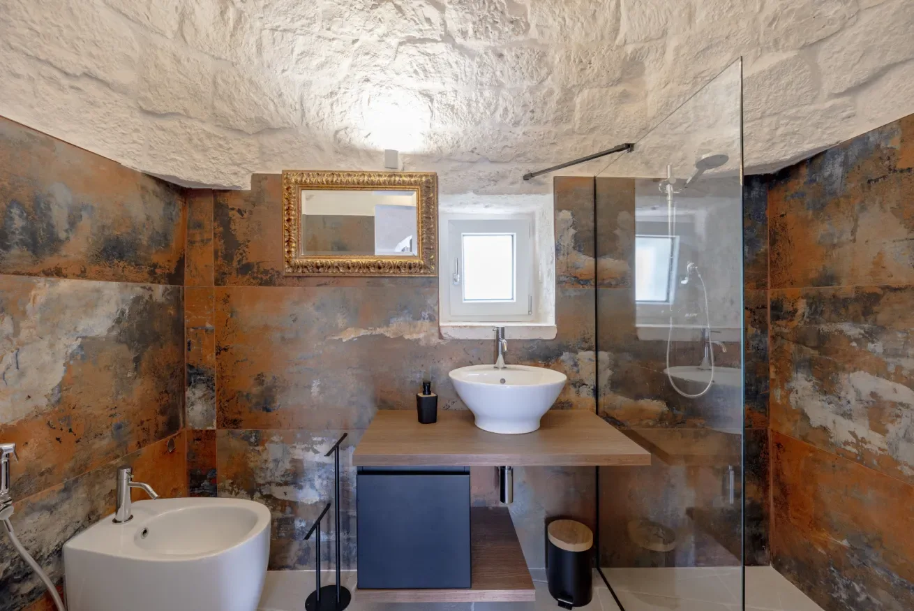 A bathroom with a white sink, vessel basin, and glass shower.