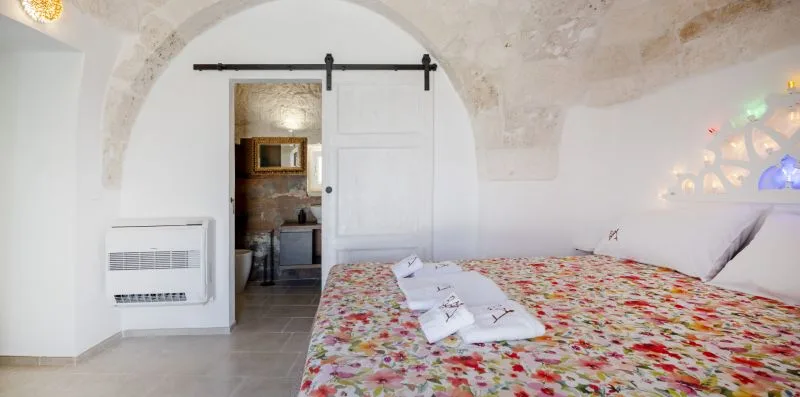 A bedroom with a floral bedspread and an arched stone ceiling.