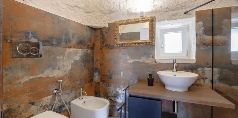 A bathroom with a wall-mounted mirror, sink, and toilet.