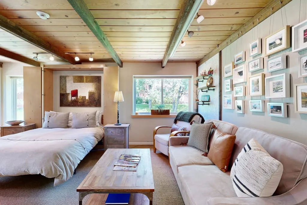 A bedroom with a bed and a sofa beside a wall of framed pictures.