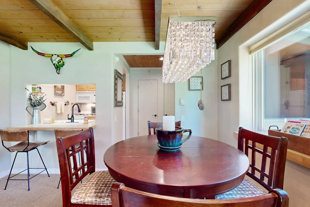 A dining area with a round wooden table beneath a hanging light.