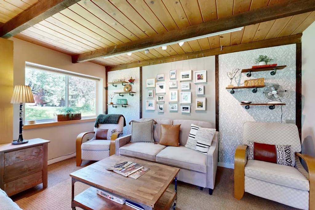 A living room with seating, framed pictures, and a large window.