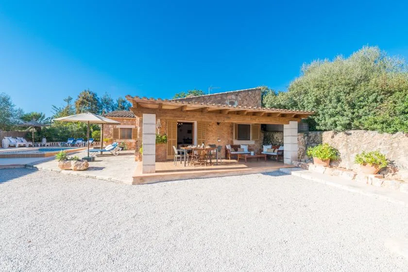 A stone house opens onto a covered patio with outdoor seating.