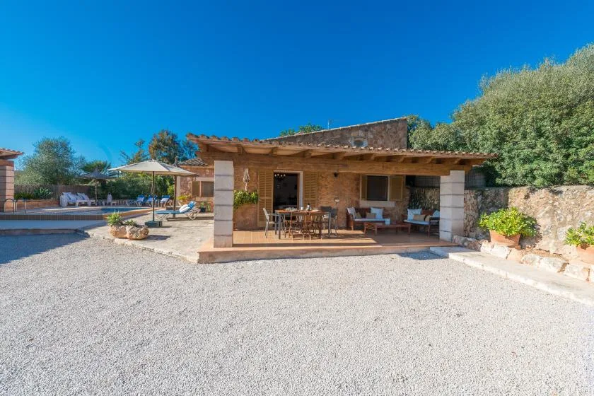 A stone patio with shaded outdoor seating beside a gravel courtyard.