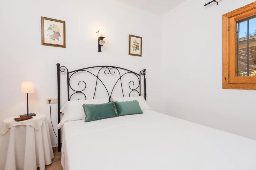 A bedroom with a white bed, decorative black headboard, and window.