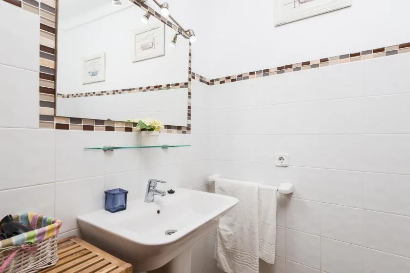 A tiled bathroom with a sink, mirror, and towel.