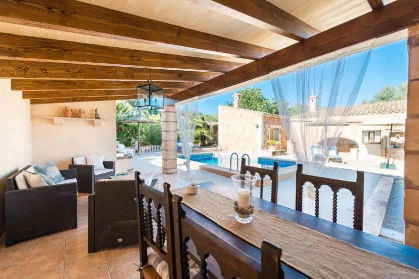 A covered dining area opens onto a patio with a swimming pool.