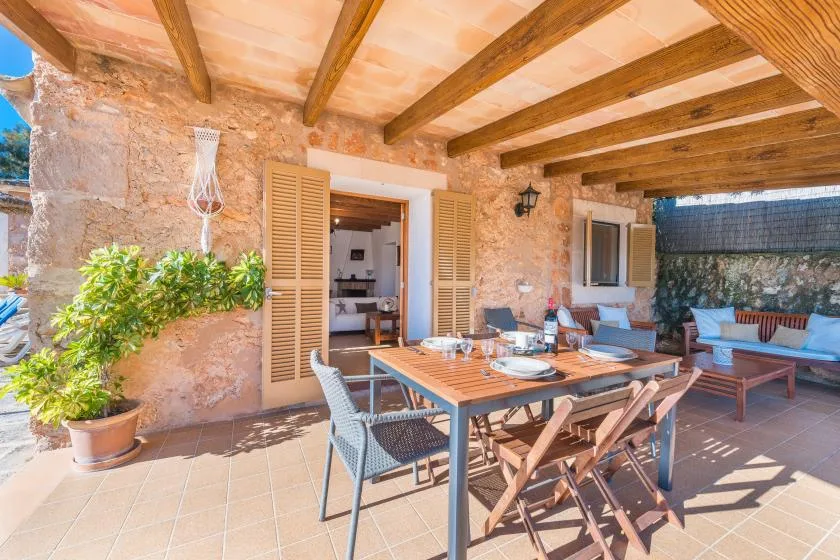A covered stone patio has an outdoor dining table and seating.