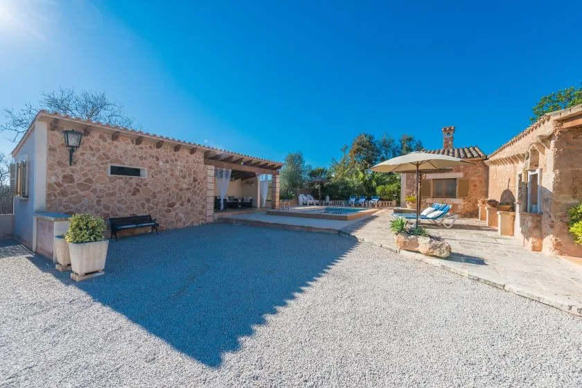 A stone courtyard with a swimming pool, outdoor seating, and a sun umbrella.