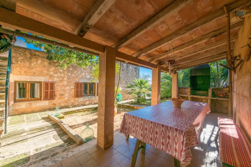 A covered patio has a dining table beside a sunlit courtyard.
