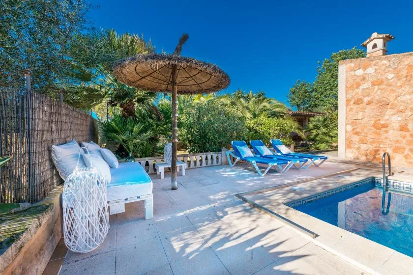 An outdoor pool area with blue loungers and a large shade umbrella.