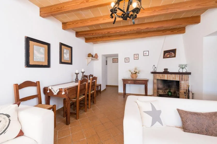A living and dining room with wooden ceiling beams and a fireplace.