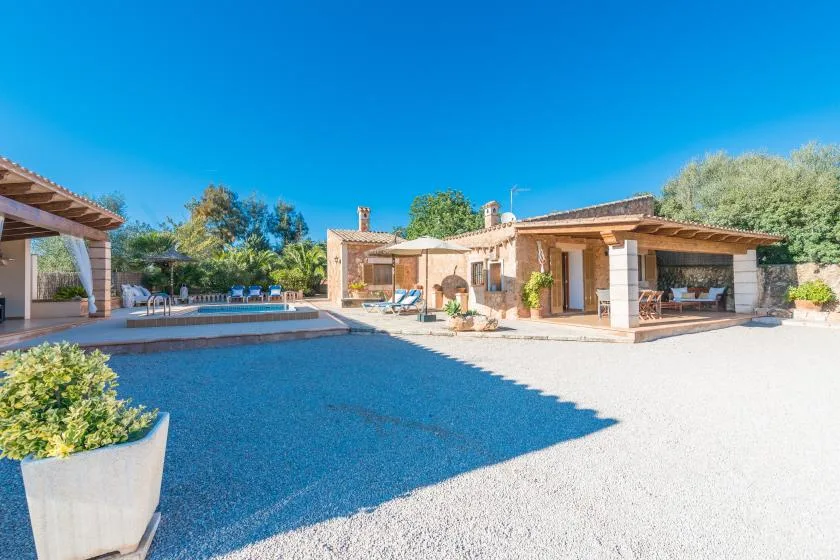 An outdoor pool beside a low stone building and covered patio.