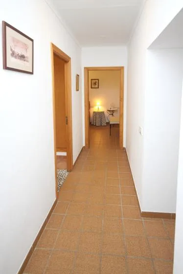 A tiled hallway leads to a warmly lit room with a table and seating.