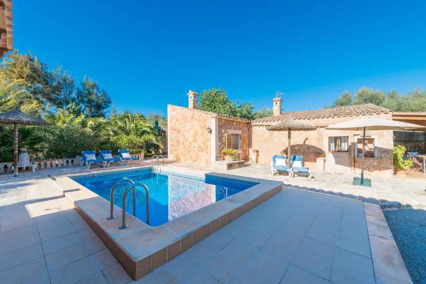 An outdoor pool sits beside a single-story building, with lounge seating nearby.