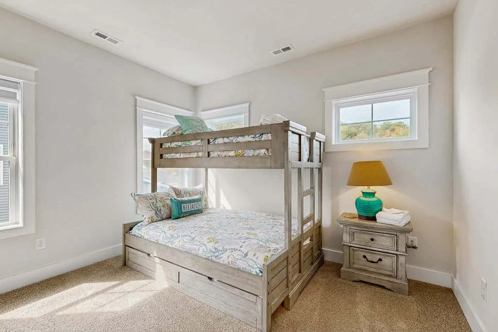 A bright bedroom features a wooden bunk bed and a bedside table.
