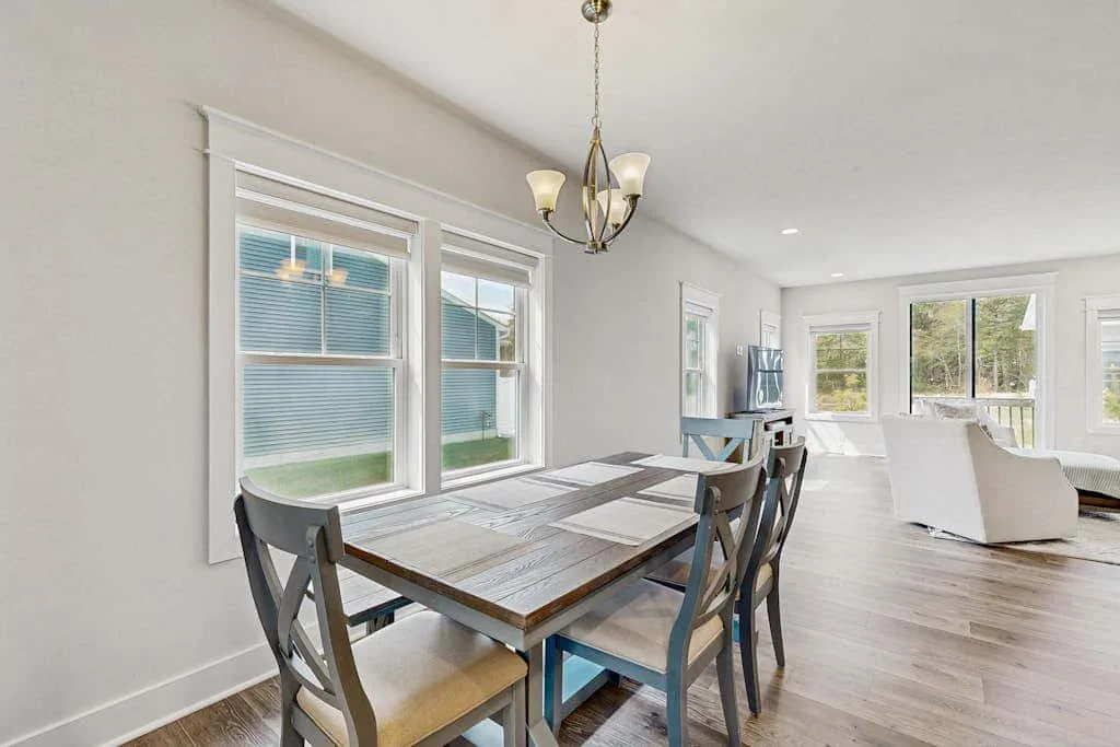 Dining area with a table and chairs beside large windows.