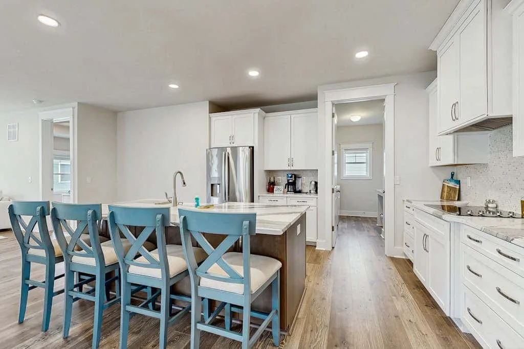 A bright kitchen with a dining island and blue seating.