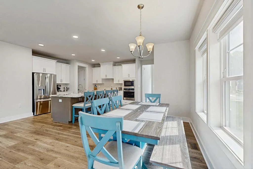 An open kitchen and dining area with blue seating around a long table.