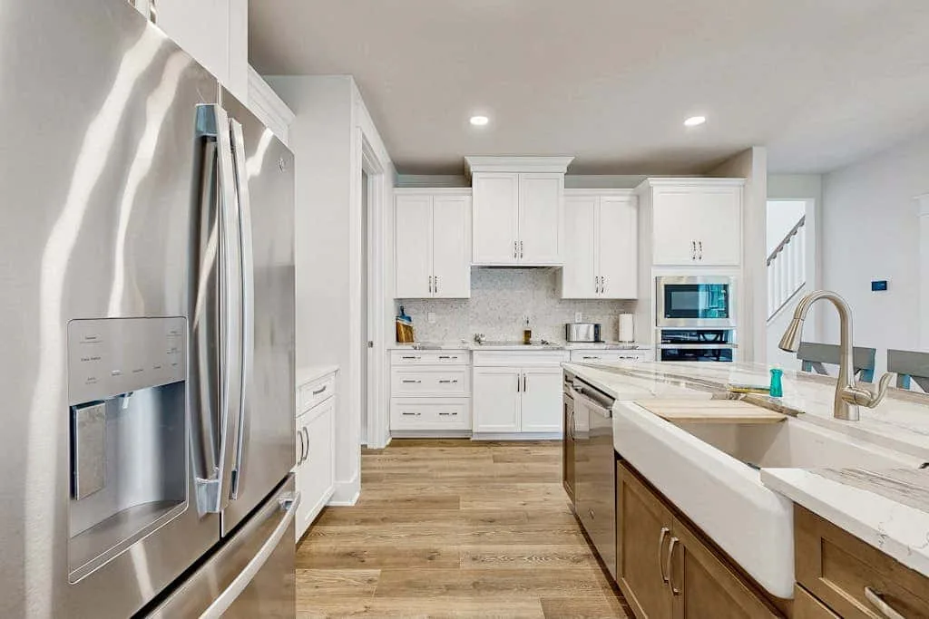 A bright kitchen with white cabinets, stainless steel appliances, and a large island.