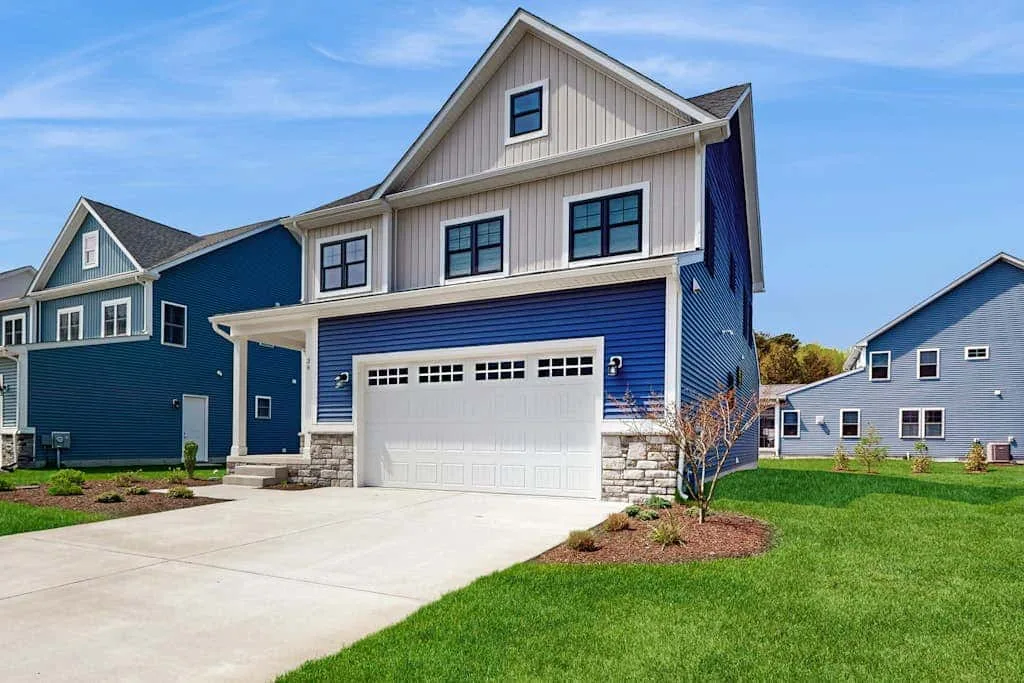 A blue-and-white two-story house with a garage and driveway.
