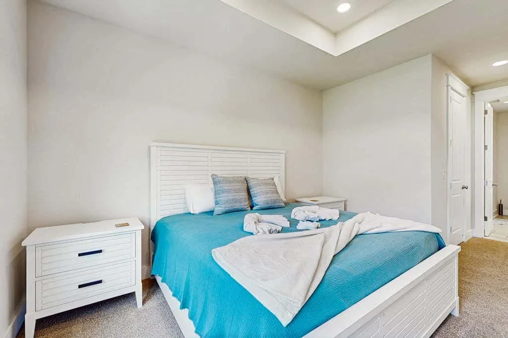 A bedroom with a bed dressed in blue and white linens.