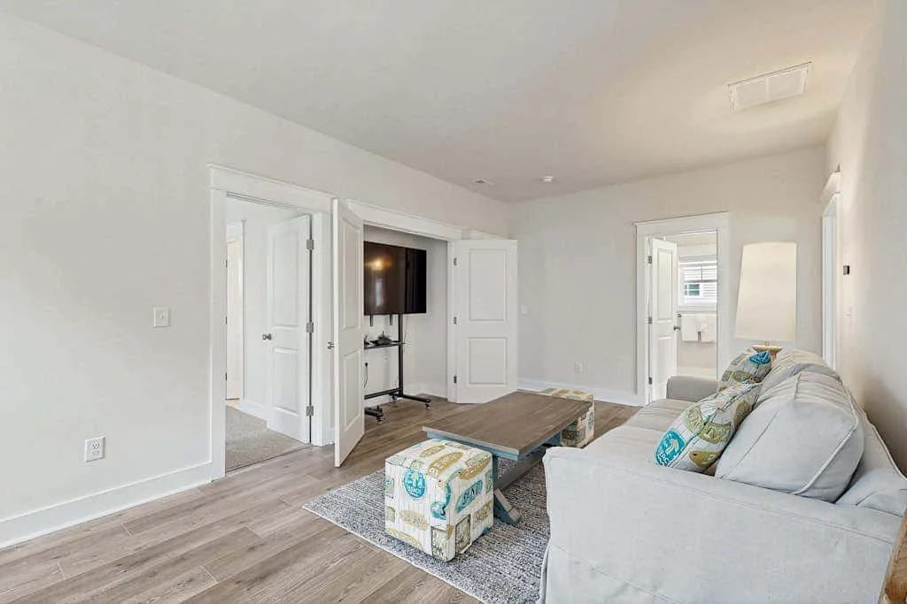 A bright living room with light seating and a television.