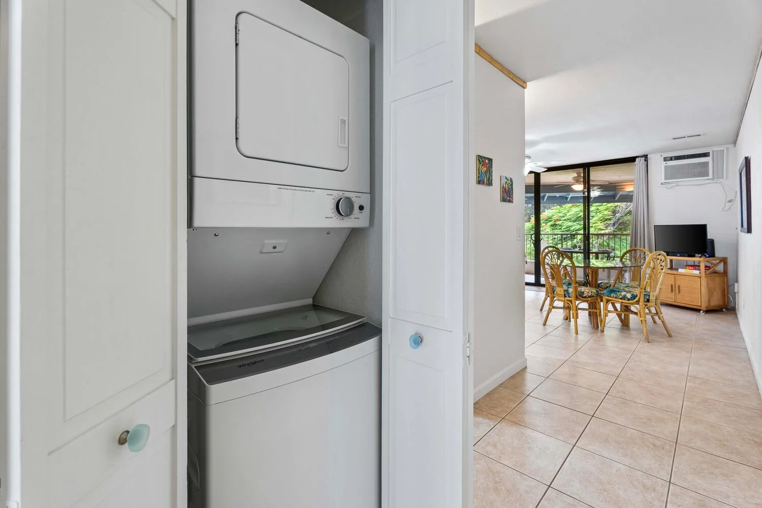 Una zona de lavandería con lavadora y secadora apiladas da a un comedor.