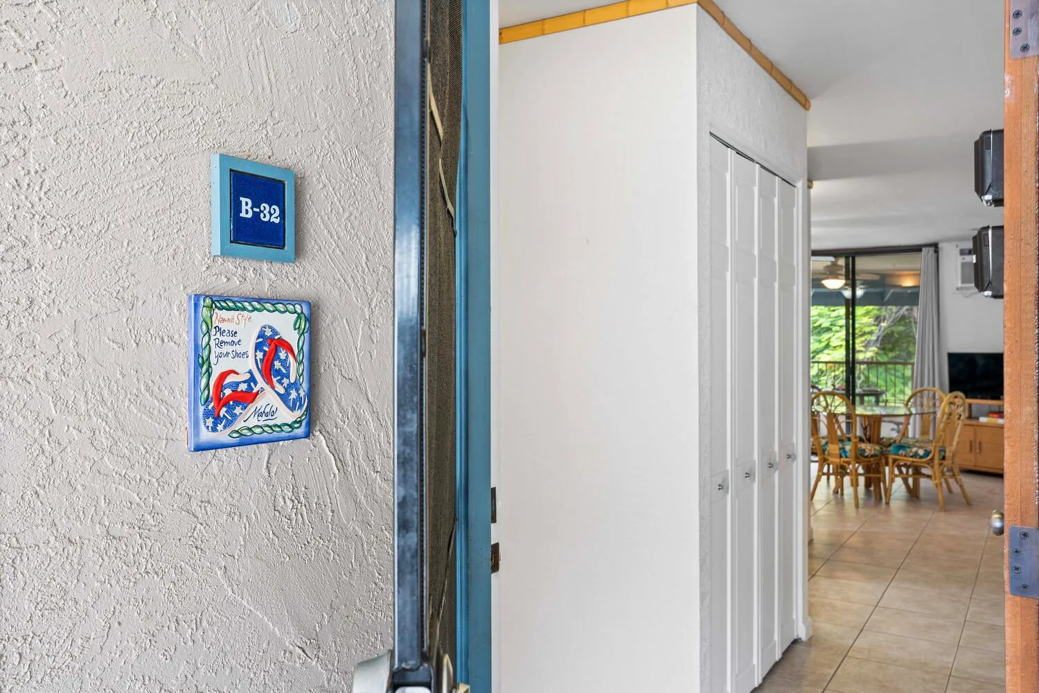 Una puerta abierta muestra un pasillo con suelo de baldosas que conduce a un comedor.