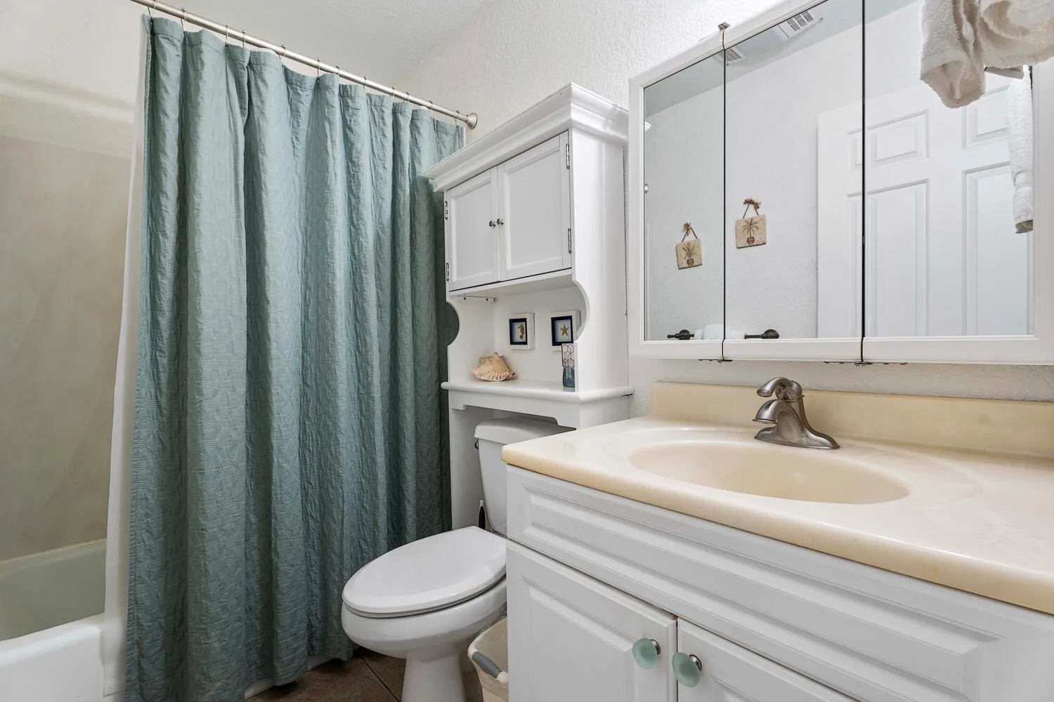 Un baño con lavabo, inodoro y cortina de ducha verde.