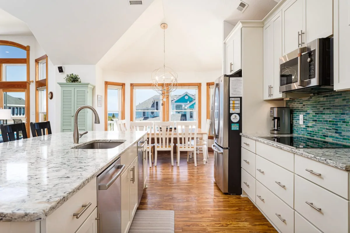 Una cocina luminosa con una isla central y una mesa de comedor junto a las ventanas.