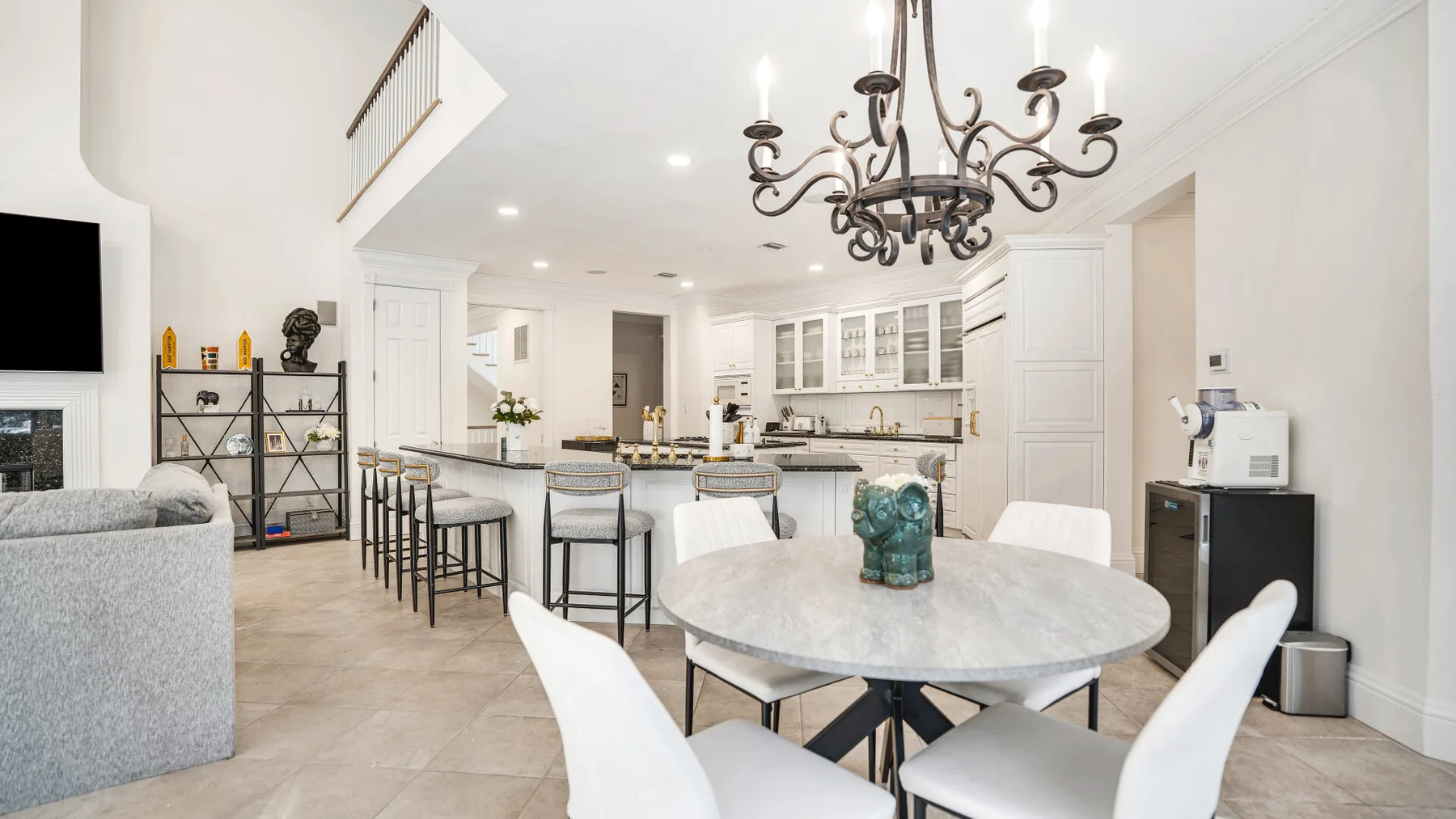 A bright open-plan kitchen and dining area with a round table and island seating.