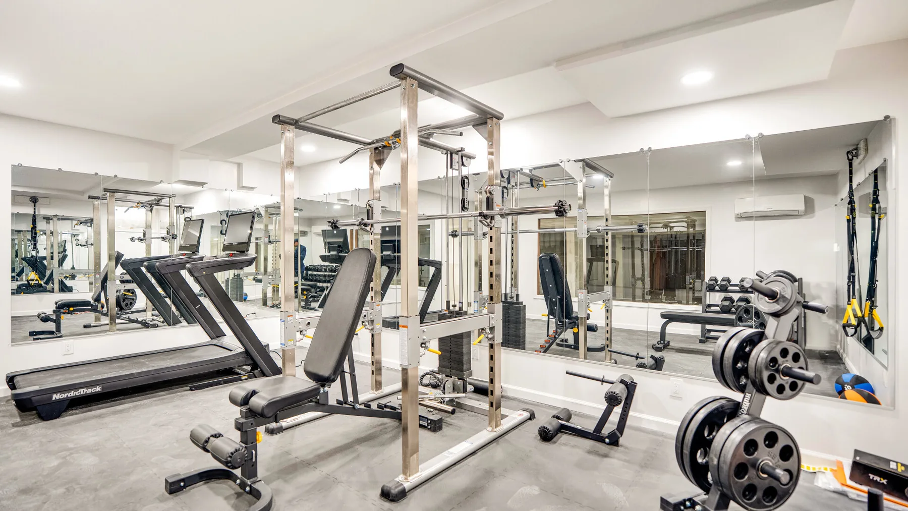 A bright indoor gym with exercise machines and weight-training equipment.
