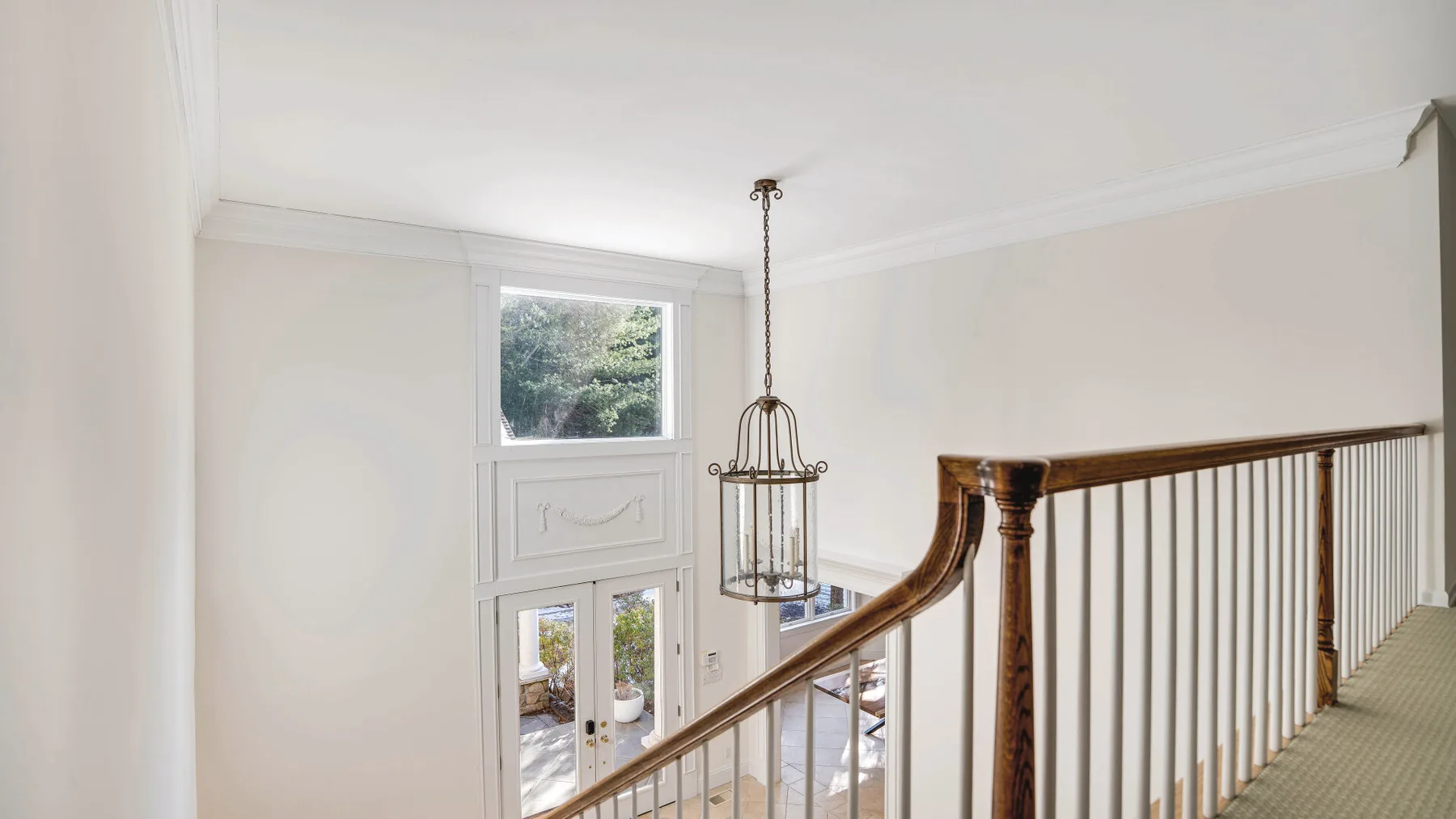 An interior staircase with a wooden handrail and a hanging light.