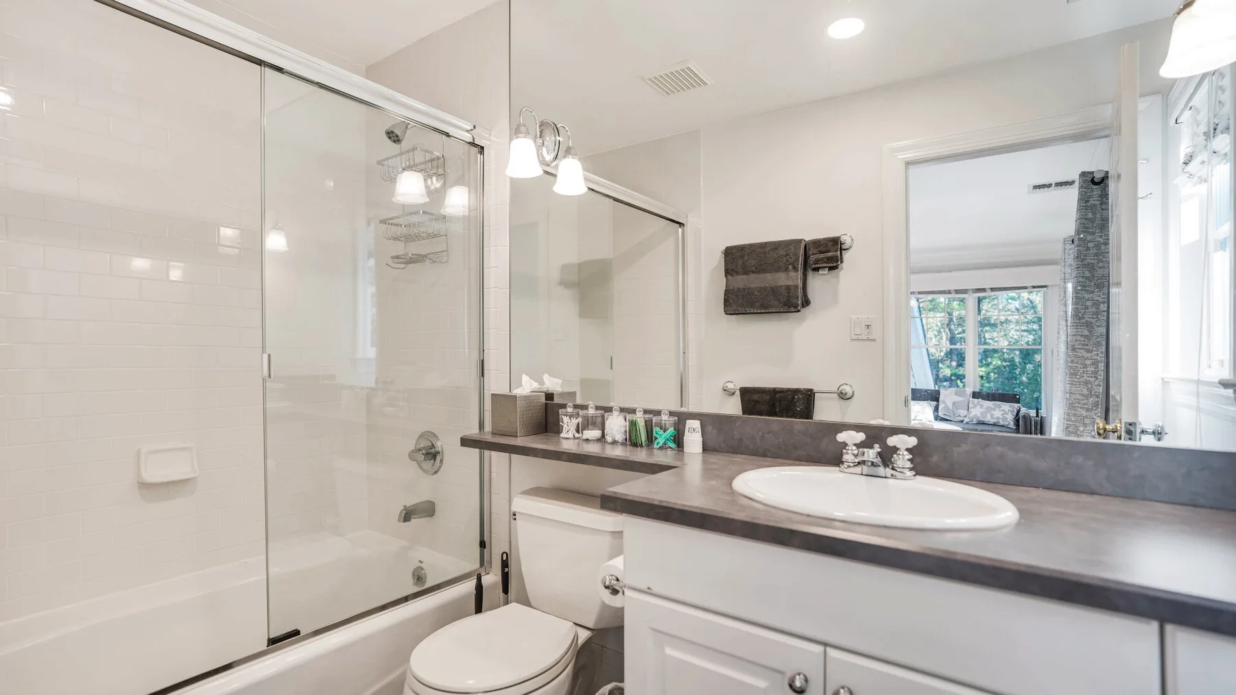 A bright bathroom with a glass shower and a wide vanity.