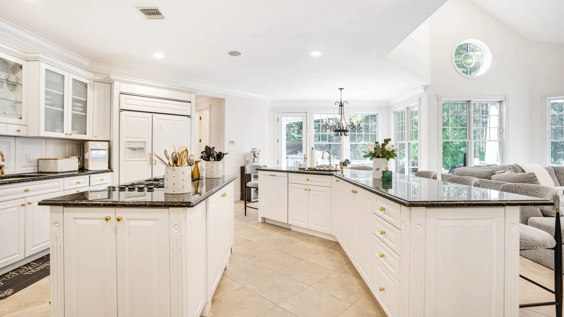 A bright kitchen with white cabinetry, central islands, and large windows.