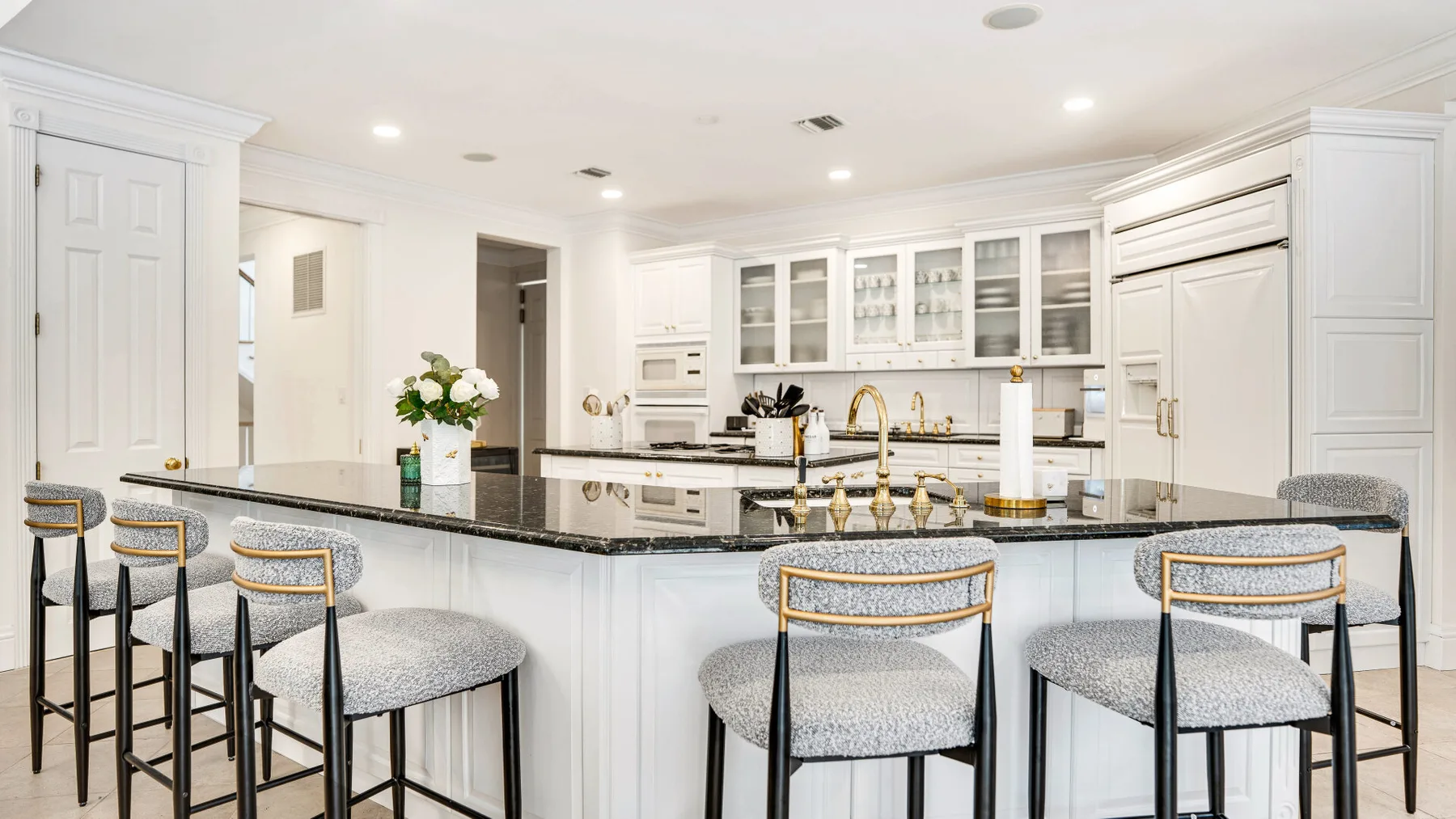 A bright white kitchen with a large island and stools.