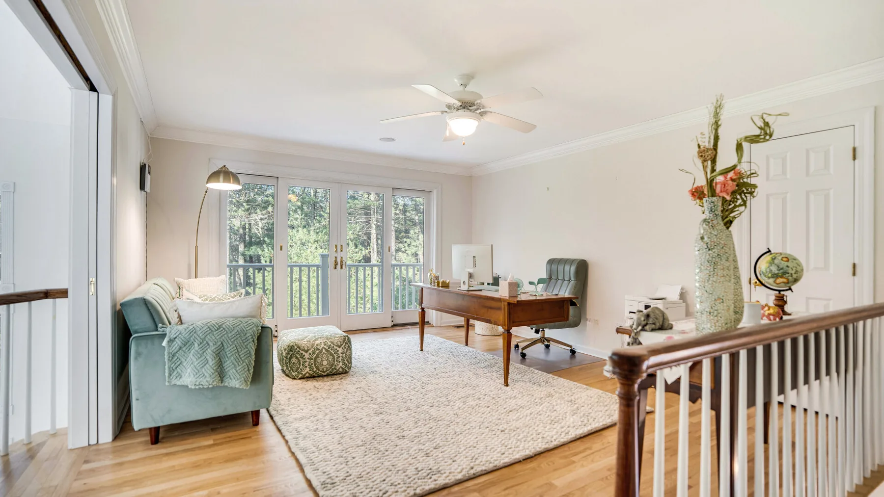 A bright living room with a seating area, desk, and large windows.