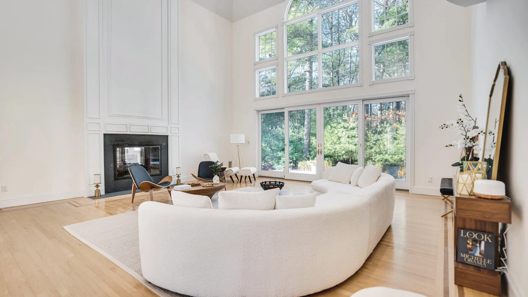 Una sala luminosa con asientos curvos y grandes ventanas con vistas a los árboles.