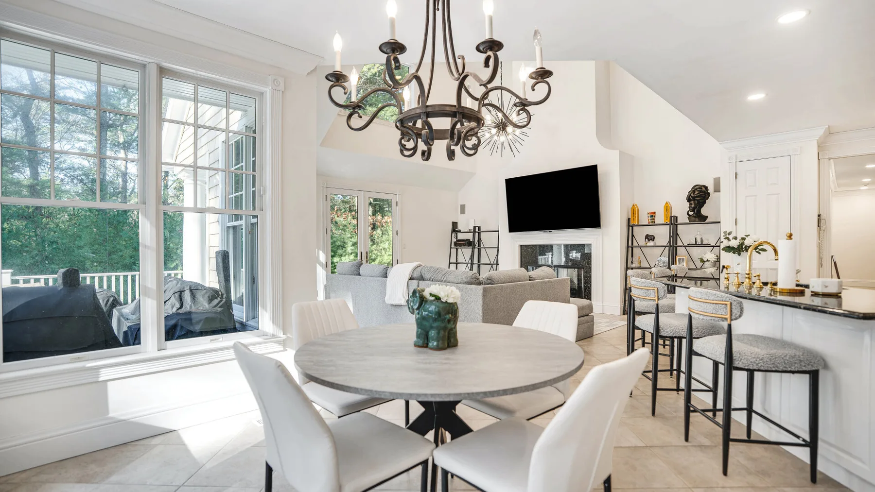 A bright open-plan dining and living area with a table, seating, and large windows.