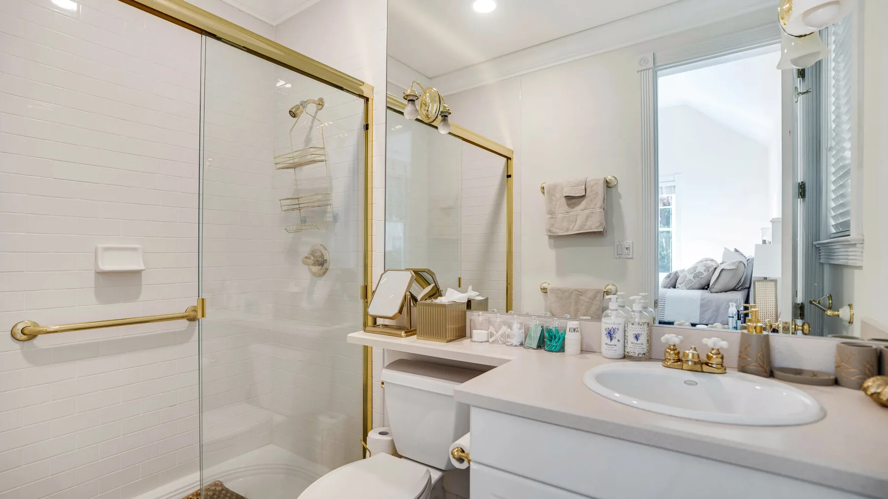 A bright bathroom with a glass shower and a sink vanity.