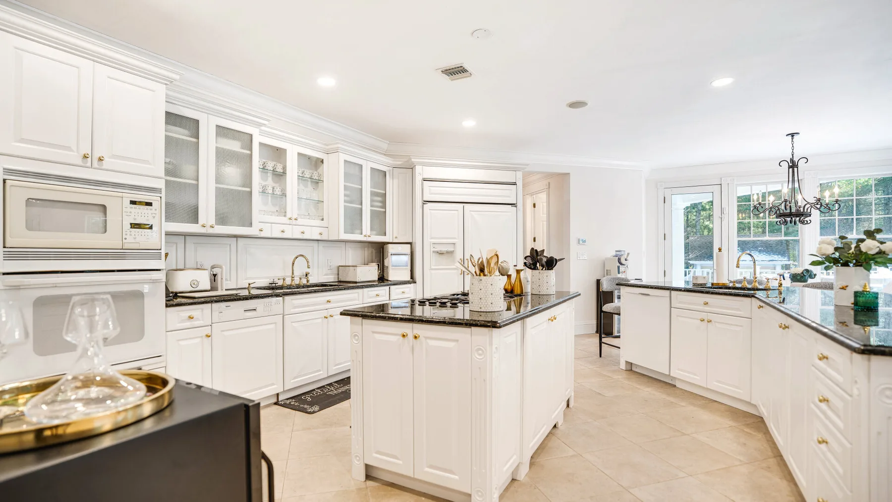 A bright white kitchen with a central island and built-in appliances.