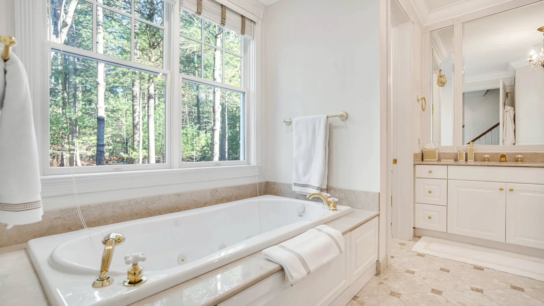 A bright bathroom with a large bathtub beside wide windows.