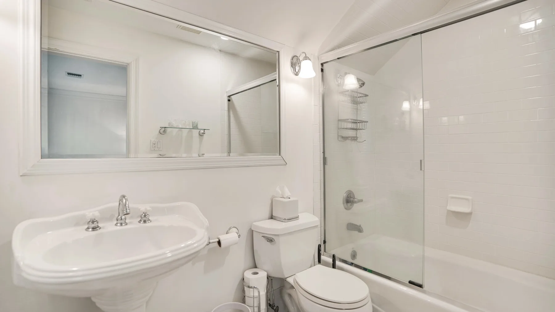A bright bathroom with a sink, toilet, and glass shower.
