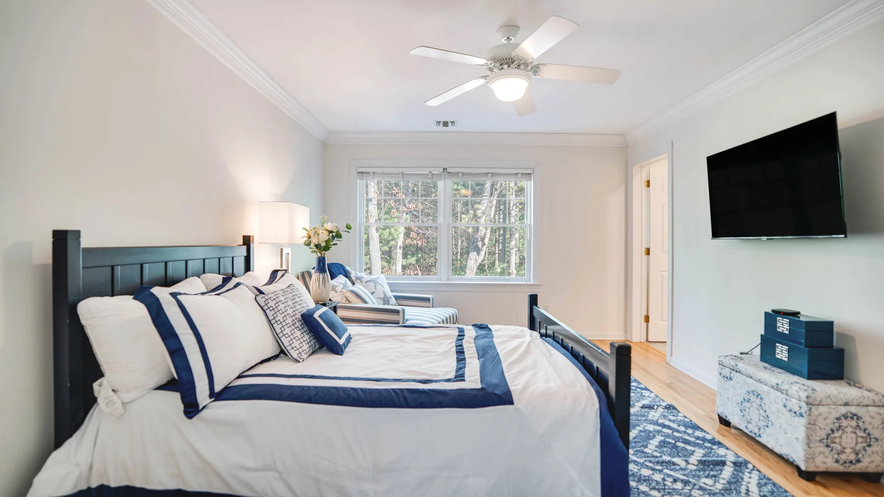 A bedroom with a bed, a window, and a wall-mounted television.