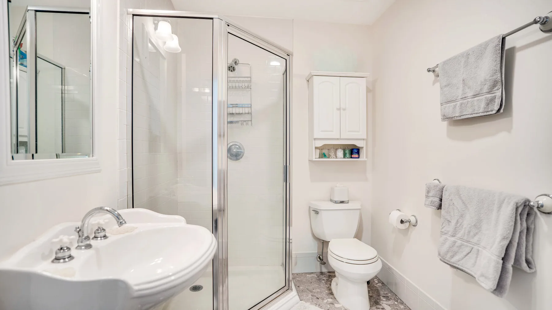 A bright bathroom with a glass shower, sink, and toilet.