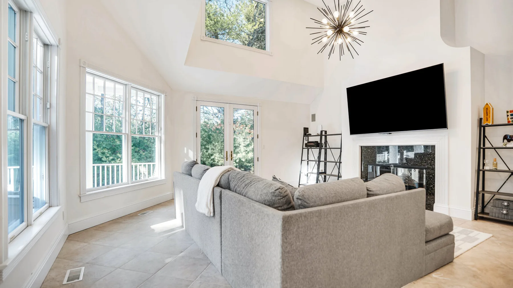 A bright living room with large windows and seating around a fireplace.