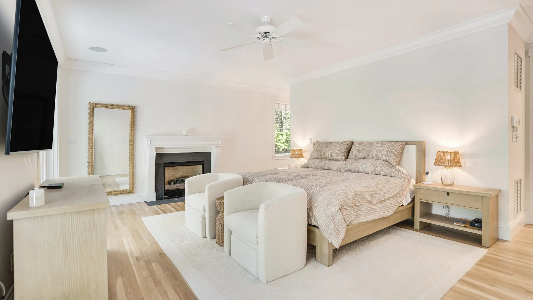 A bright bedroom with a large bed and two upholstered chairs.