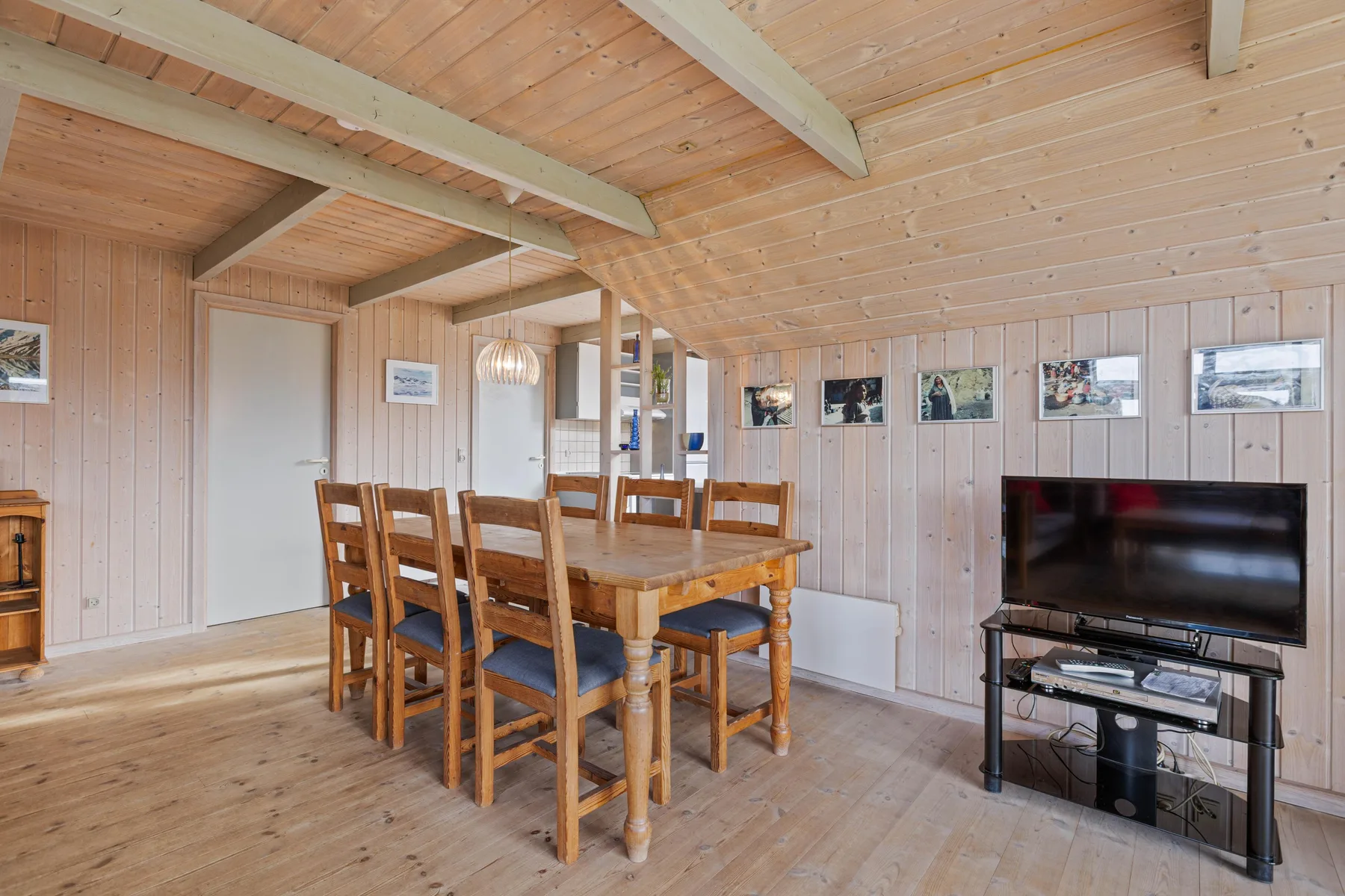 Un comedor revestido de madera con una mesa, asientos y un televisor.